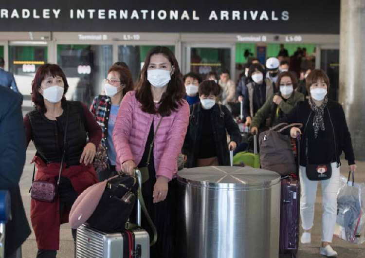 Các hành khách đeo khẩu trang để tự bảo vệ khi hạ cánh xuống sân bay Los Angeles, Mỹ. Ảnh: AFP.